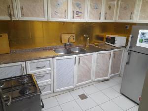 una cucina con mobili bianchi, un lavello e un frigorifero di Yasliving EXTN a Abu Dhabi Altre 13 foto