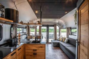 a kitchen and living room of an rv with a couch at The Côôn Tinyfloatinghome in Den Bosch