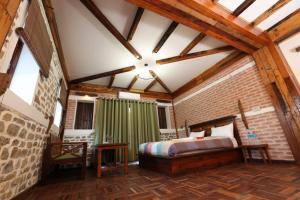 The End Of The Universe boutique hotel في ناغاركوت: غرفة نوم بسرير وجدار من الطوب