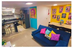 a living room with a blue couch and a kitchen at Apartamentos com 2 quartos na Praia de Itapema bairro Meia Praia in Itapema