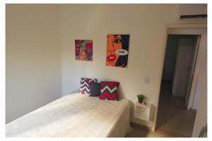 a bedroom with a bed and three paintings on the wall at Apartamentos com 2 quartos na Praia de Itapema bairro Meia Praia in Itapema +56 photos