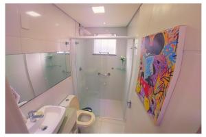 a bathroom with a shower and a painting on the wall at Apartamentos com 2 quartos na Praia de Itapema bairro Meia Praia in Itapema
