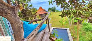 a wooden bed with a blue pillow in a tree at A Mango Tree House with a private swimming pool in Tegallengah
