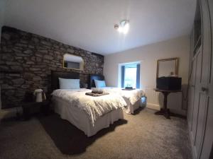 a bedroom with two beds and a stone wall at Coach & Horses Inn in Crickhowell