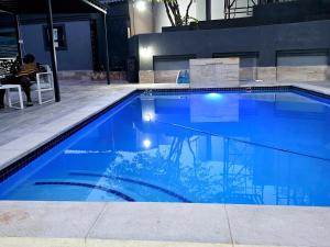 a blue swimming pool with a person sitting in a chair next to it at Batuka Damview Lodge in Tshakhuma