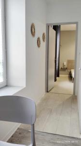 a white room with a chair and a hallway at Studios ou Chambre SDB avec extérieur centre-ville Ribérac in Ribérac