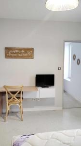 a living room with a table and a tv on a wall at Studios ou Chambre SDB avec extérieur centre-ville Ribérac in Ribérac