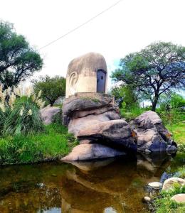 a building sitting on top of a rock next to a pond at Cabaña El Chaparral Villa Dolores, Traslasierra 4 in Villa Dolores +8 photos