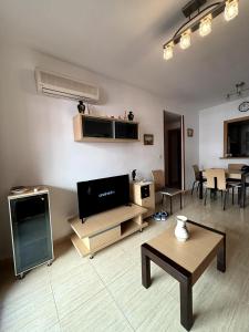 ein Wohnzimmer mit Fernseher und Tisch in der Unterkunft Apartamento vacacional cerca al mar - OROPESA DEL MAR in Oropesa del Mar