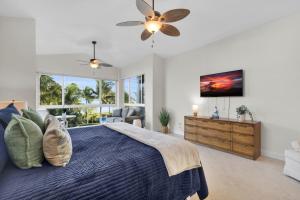 a bedroom with a large bed with a ceiling fan at Deja Blue at Mariner's Club, 2 Pools, Fitness Center, Marina and more in Key Largo +49 photos
