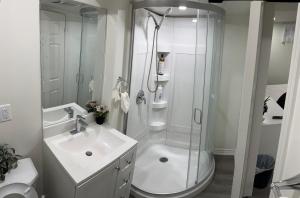 a white bathroom with a shower and a sink at B02 luxurious suite in Mississauga