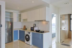a kitchen with blue and white cabinets and a washer at Greystone Continew Residensi in Kuala Lumpur