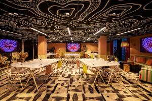 a restaurant with tables and chairs and a ceiling with purple at Mama Shelter Dijon in Dijon