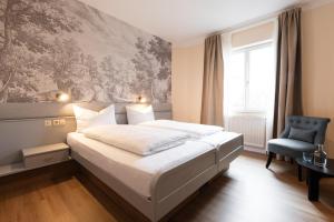 a bedroom with a white bed and a blue chair at Boutiquehotel Drei Ringe Schwörstadt - Rheinfelden in Schwörstadt +23 photos