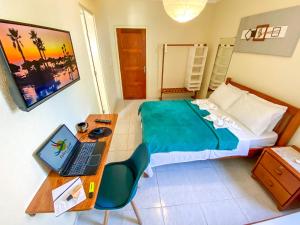 a bedroom with a desk and a bed with a laptop at Refúgio Pousada Fortaleza in Fortaleza