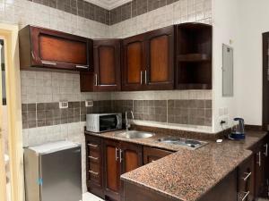 une cuisine avec des armoires en bois et un réfrigérateur en acier inoxydable dans l'établissement Elegant Studio at Celia Compound-New Administrative Capital, à Madīnat al Amal 7 autres photos