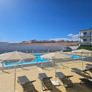 een groep stoelen en parasols naast een zwembad bij La Preciosa Suite Apartment in Antigua