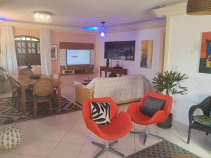 a living room with red chairs and a dining room at Sobrado estilo Colonial in Salvador