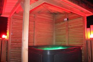 una vasca idromassaggio in una stanza di legno con luci rosse di Les cabanes de Labrousse a Saint-Julien-Labrousse