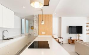 a kitchen with white cabinets and a living room at Penthouse with Terrace near Gran Via and Camp Nou in Barcelona +18 photos