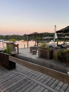 a wooden deck with tables and umbrellas on a beach at NEU! Ferienhaus Schöne Aussicht direkte Strandlage in Aurich