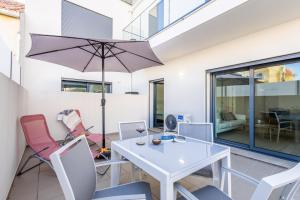 a dining room with a white table and chairs and an umbrella at Baia Mar T1 - By Smarthomes in São Martinho do Porto