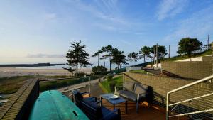 einen Balkon mit Surfbrett und Stühlen sowie einem Strand in der Unterkunft Casa Del Mar in San Vicente de la Barquera