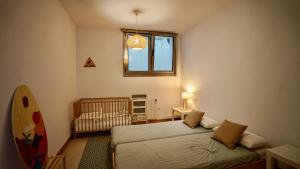 1 Schlafzimmer mit 2 Betten, einem Fenster und einem Kinderbett in der Unterkunft Casa Del Mar in San Vicente de la Barquera