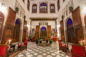 a lobby with chairs and tables and stained glass windows at Riad - Dar Al Andalous in Fès