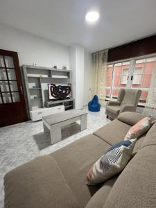Una sala de estar con un sofá y un televisor. en Apartamento RUAL, en Sanxenxo