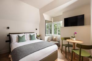 Un dormitorio con una cama, una mesa y un televisor. en FiveM West Hampstead - North, en Londres