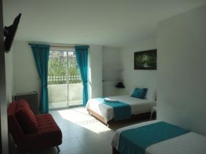 a bedroom with two beds and a chair and a window at Brizzamar Hotel in Santa Marta