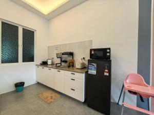 a kitchen with a black refrigerator and a pink stool at Langkawi Simfoni Luxury Suite 11 in Kuah