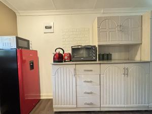 eine Küche mit einem roten Kühlschrank und weißen Schränken in der Unterkunft Heartstone's Rest Cottage in Fouriesburg