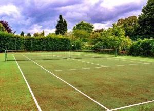 a tennis court with a net on a field at Finest Retreats - Berry Pen Cottage in Kingham