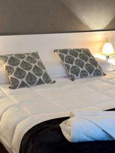 a white bed with two pillows on top of it at Piso en el corazón de Baiona con vistas al mar in Baiona