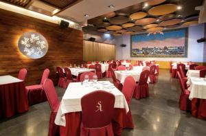 a dining room with tables and chairs and a painting at Hotel Sancho Abarca Petit SPA in Huesca