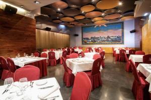 a dining room with white tables and red chairs at Hotel Sancho Abarca Petit SPA in Huesca
