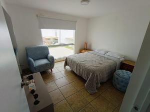 a bedroom with a bed and a chair and a window at Espectacular Casa de Playa en Asia frente al Mar in Asia