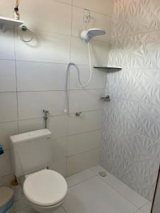 a white bathroom with a toilet and a shower at Brisa Bitingui in Japaratinga