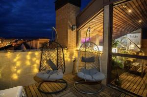 two wicker chairs sitting on a balcony at night at Hotel Sancho Abarca Petit SPA in Huesca