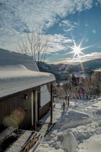 ein schneebedecktes Gebäude mit der Sonne im Hintergrund in der Unterkunft Alemiło mini - domek z balią i widokiem na Babią Górę in Zawoja