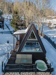 einen Pavillon im Schnee mit zwei Stühlen in der Unterkunft Alemiło mini - domek z balią i widokiem na Babią Górę in Zawoja