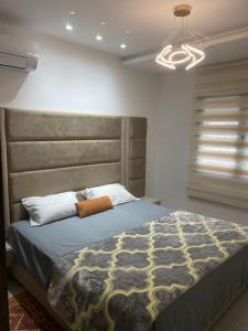 une chambre avec un grand lit avec une grande tête de lit dans l'établissement Bo app aïn zaghouén la marsa, à La Marsa