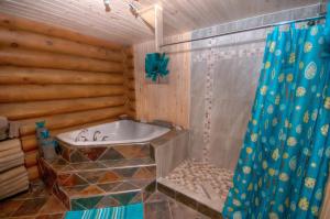 Un baño con bañera y cortina de ducha. en Le Chalet Le Bois Rond Des Ruisseaux, en Saint-Tite-des-Caps 15 fotos más