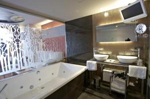 a bathroom with a tub and two sinks in it at Hotel Sancho Abarca Petit SPA in Huesca