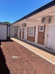 a brick building with white doors and a gravel driveway at Posada Patagónica in Neuquén