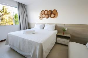una camera da letto con un letto bianco e una finestra di Casa Malu 5 Suítes 50 Metros do MAR Guarajuba-BA a Monte Gordo Altre 40 foto