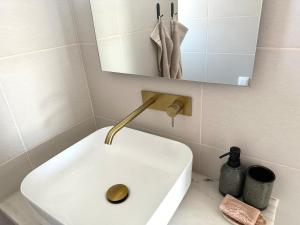 ein Badezimmer mit einem weißen Waschbecken und einem Spiegel in der Unterkunft Onda House Cozy Surf House in Odeceixe