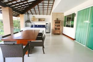 una cucina e una sala da pranzo con tavolo e sedie in legno di Casa Malu 5 Suítes 50 Metros do MAR Guarajuba-BA a Monte Gordo